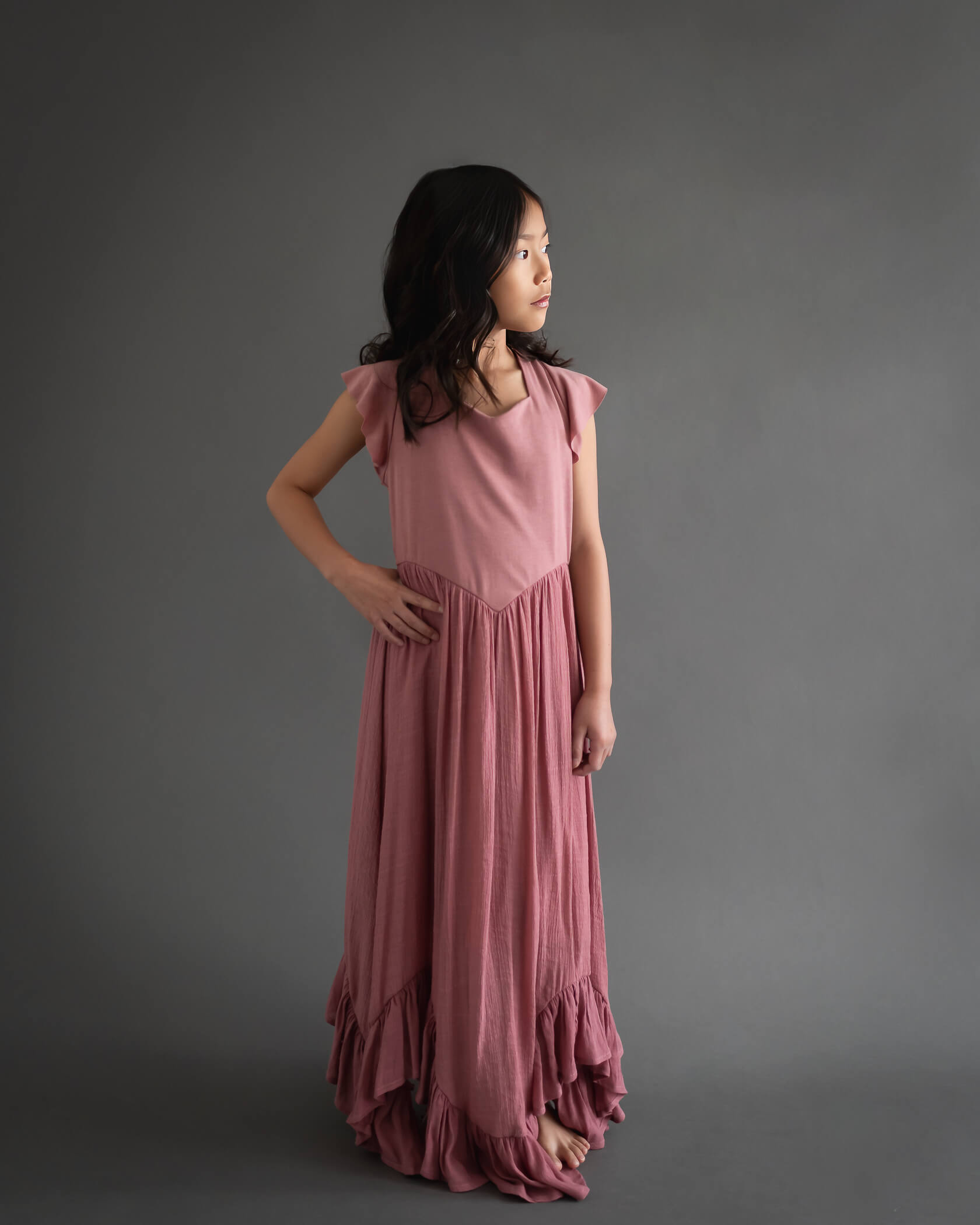 10 year old girl in long dress with hand on hip looking away
