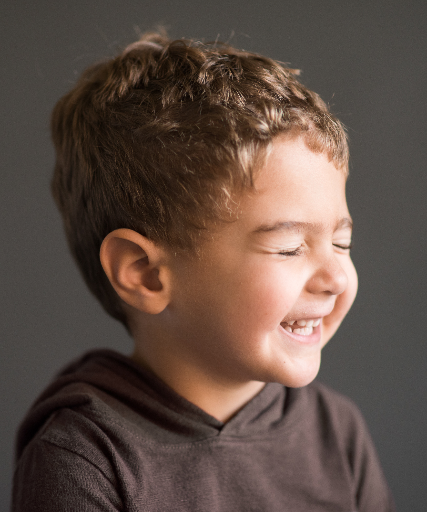 small boy laughing with eyes closed in studio session