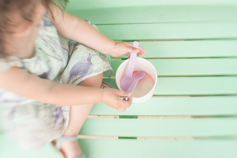 little girl having ice cream on an aqua bench