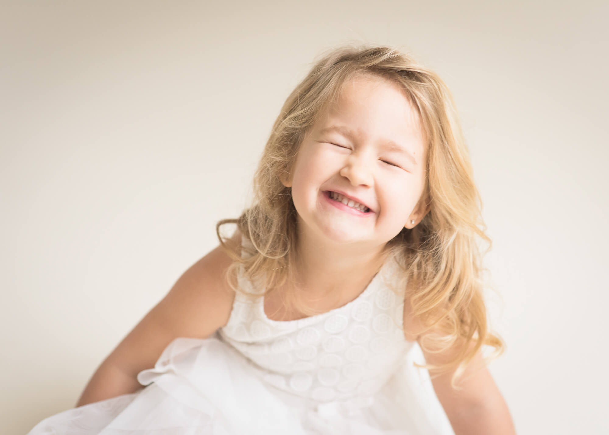 silly preschooler in studio portrait cream dress light background
