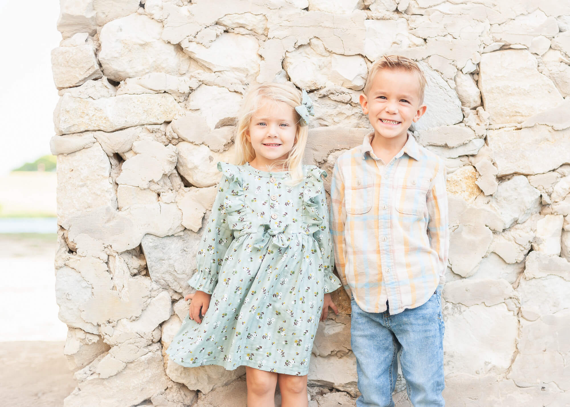 Gorgeous well-dressed kiddos against stone wall in Adriatica Village in McKinney Texas