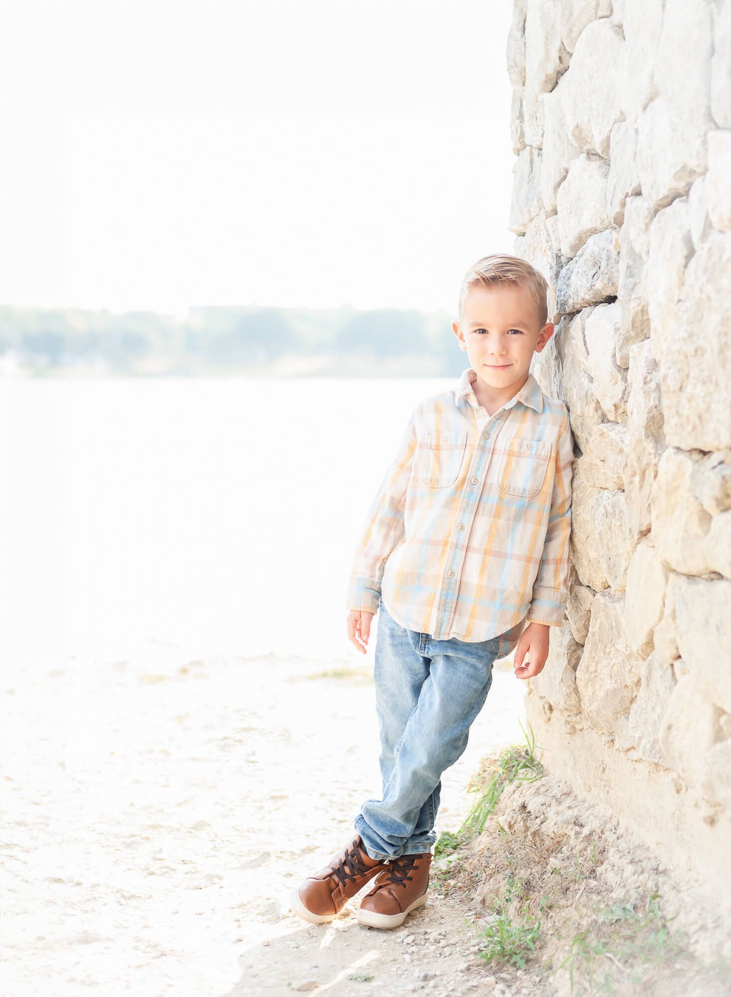 handsome little boy leaning against stone wall 
