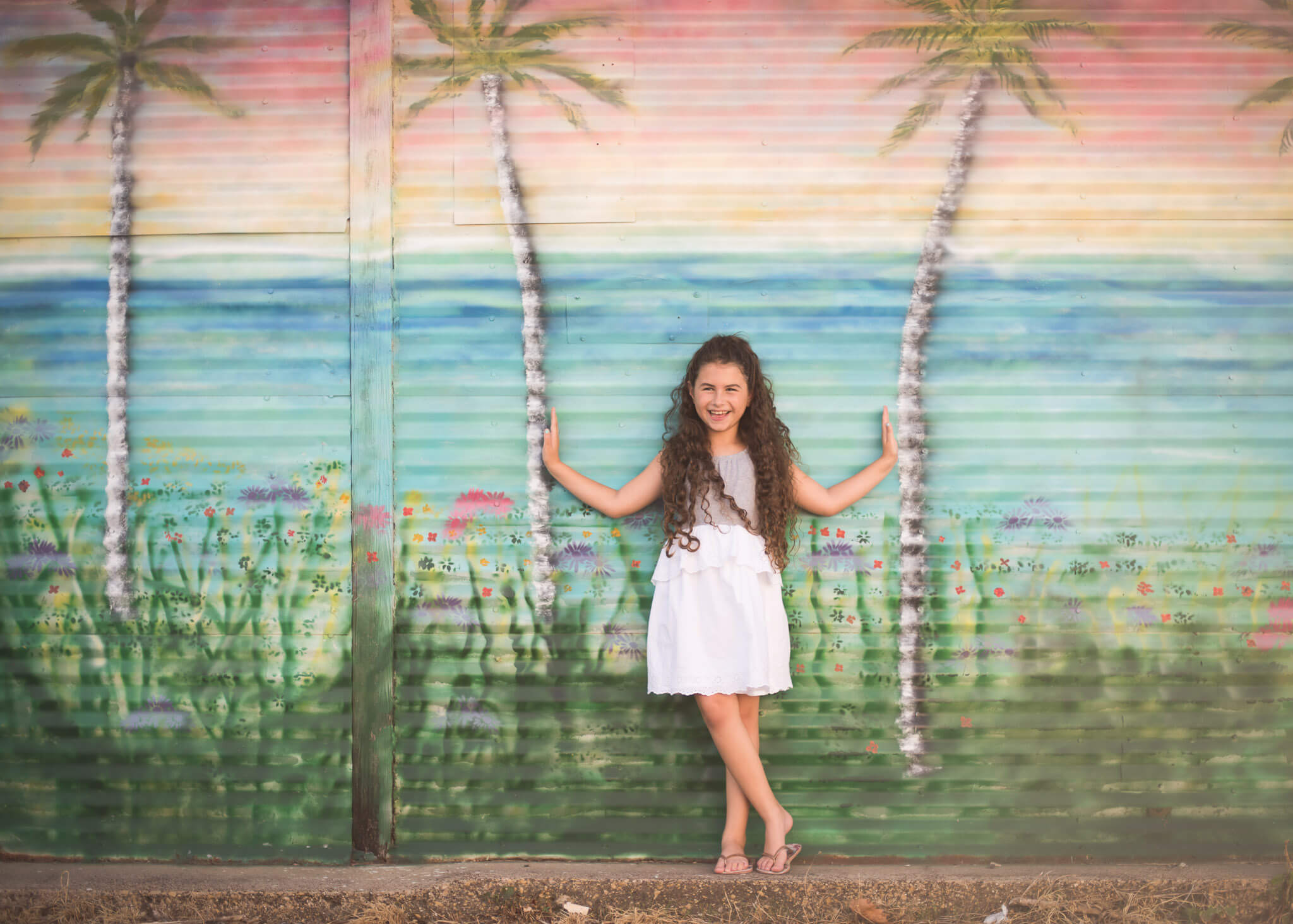 Downtown McKinney mural of palm trees with a young girl seemingly holding them up