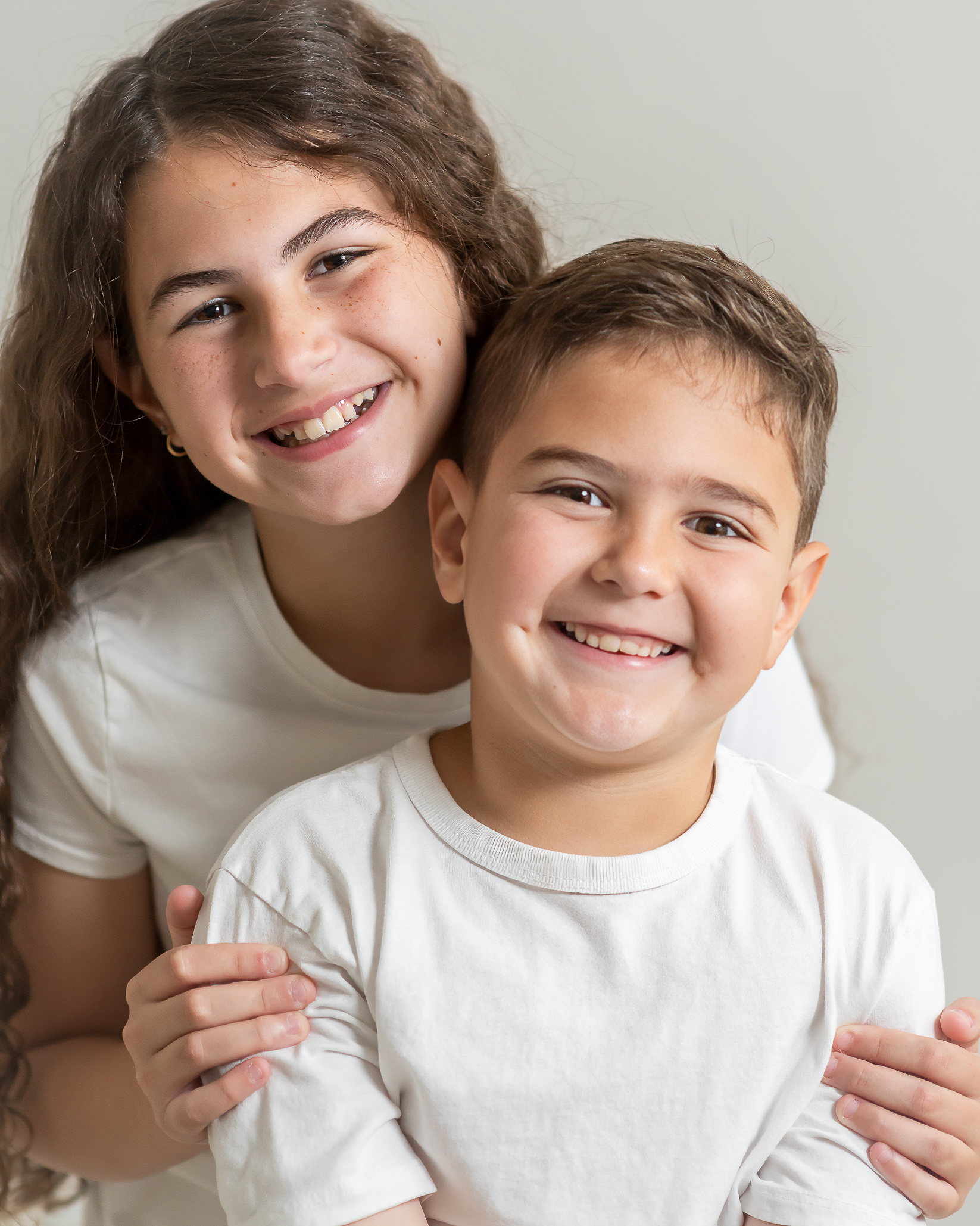 young siblings smiling showing their teeth in a childrens studio session