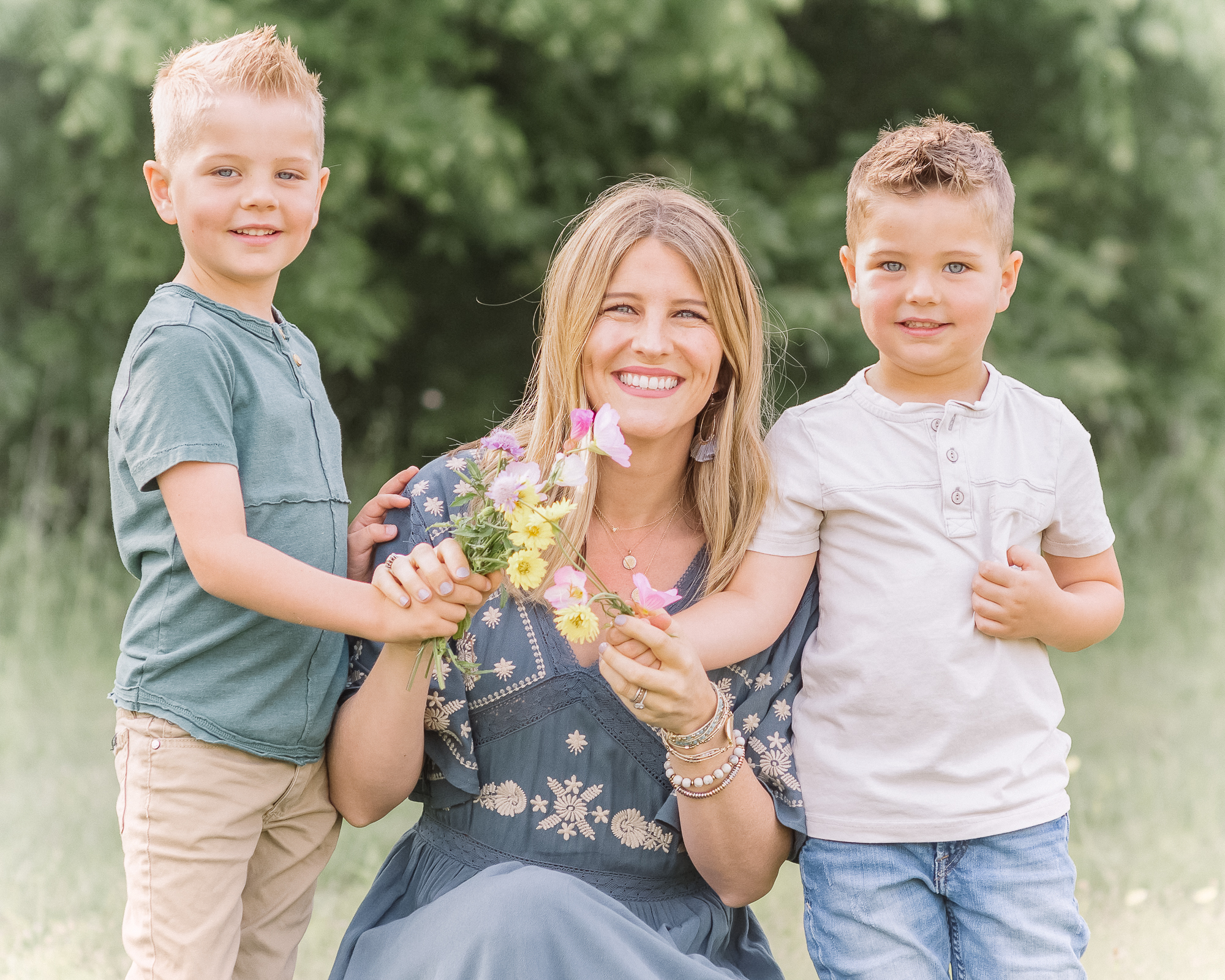gorgeous mom with 2 sons who picked flowers for her on a nature trail during family portraits
