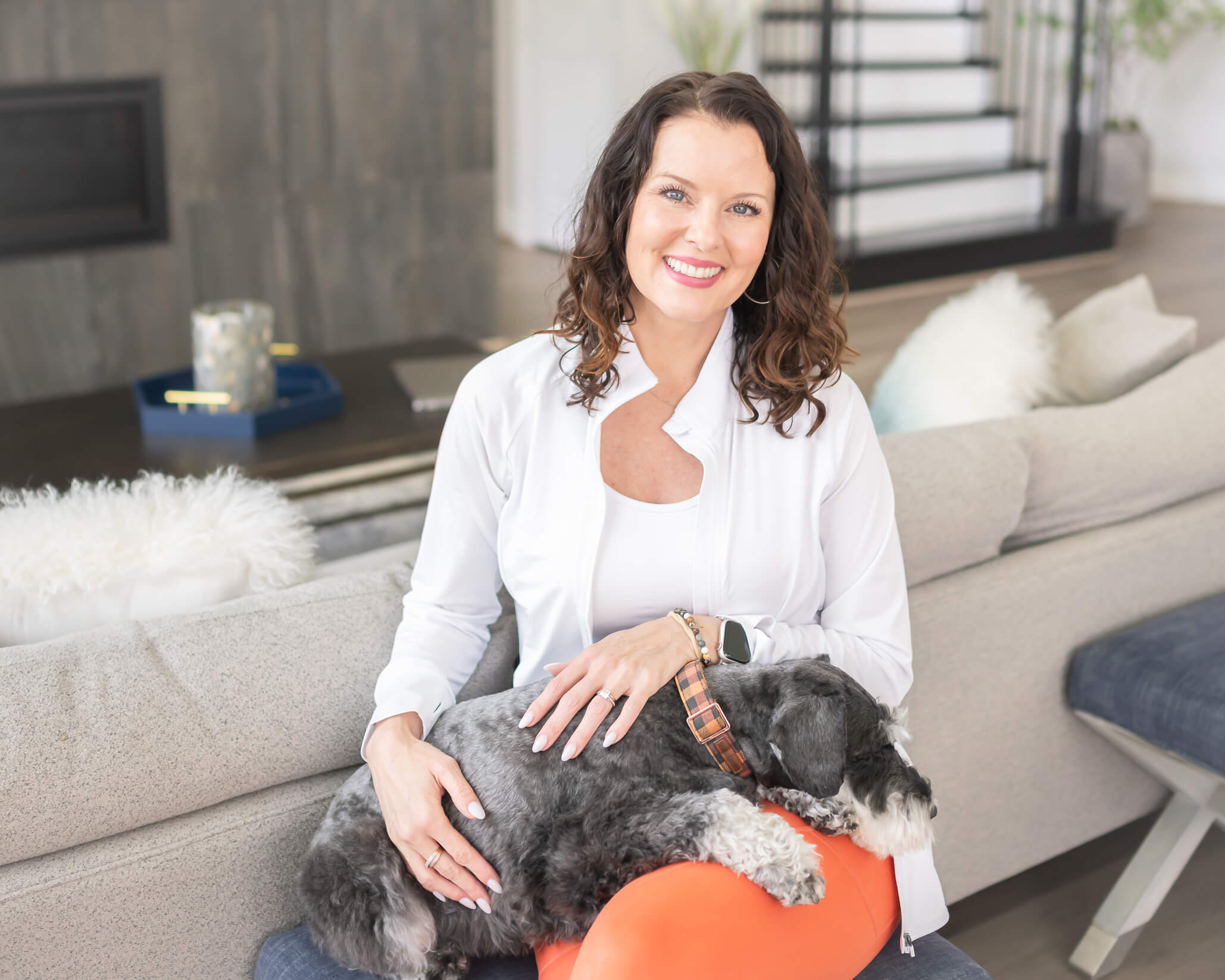 attractive woman business owner branding photo in her home in athletic wear with her dog on her lap