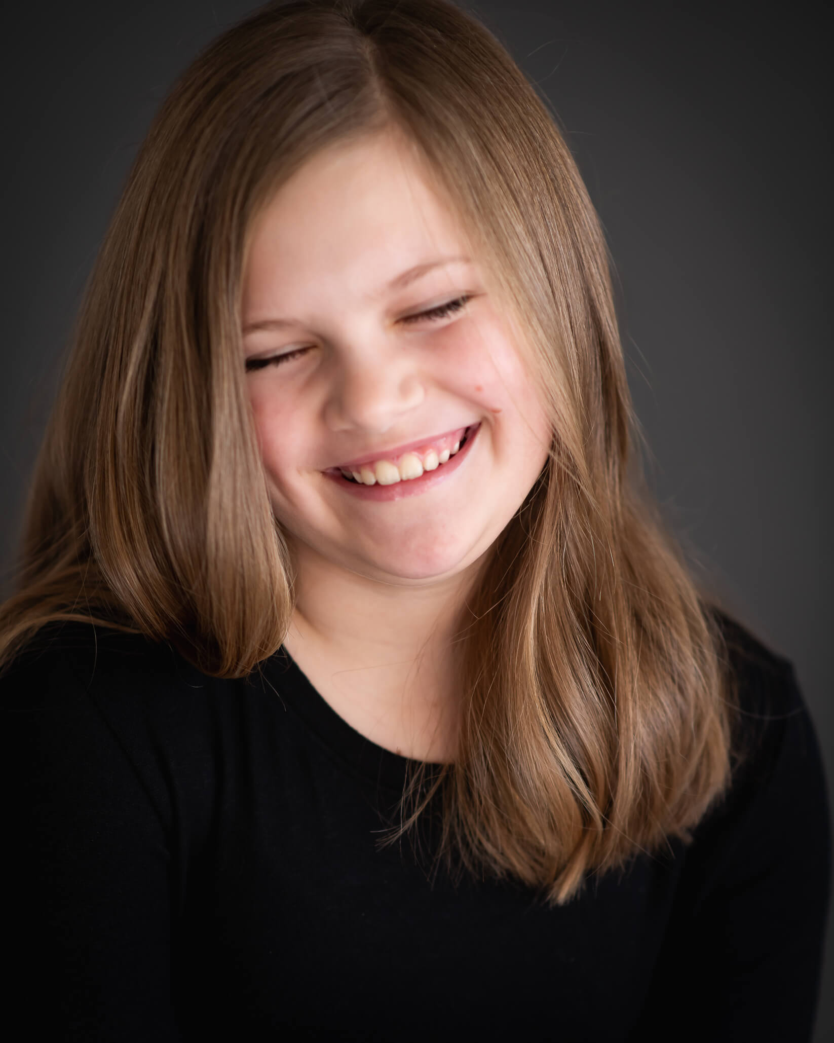 10 year old girl laughing with eyes closed in a close-up studio portrait