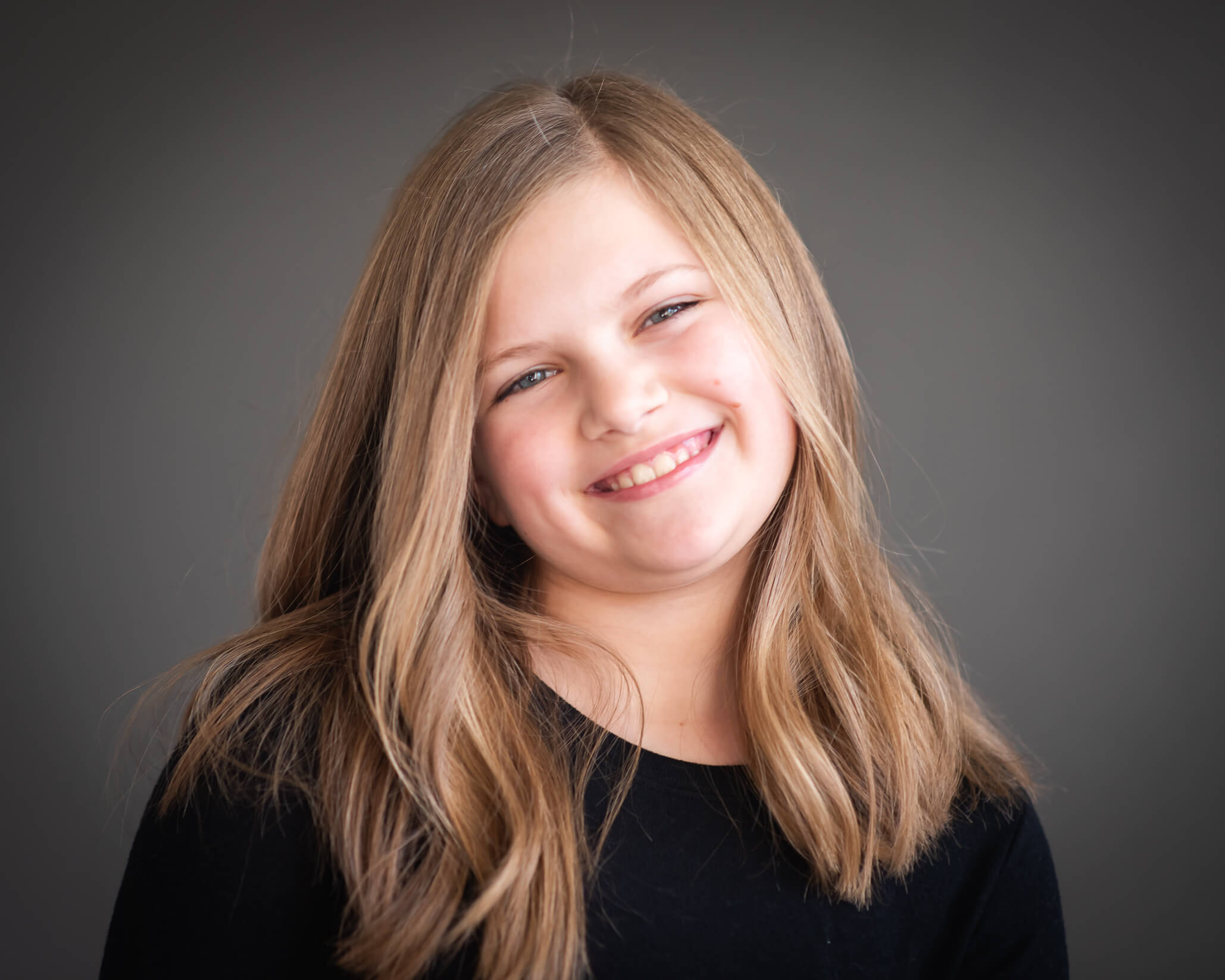 super cute 10 year old girl smiling with tilted head captured by Allison Amores Photography