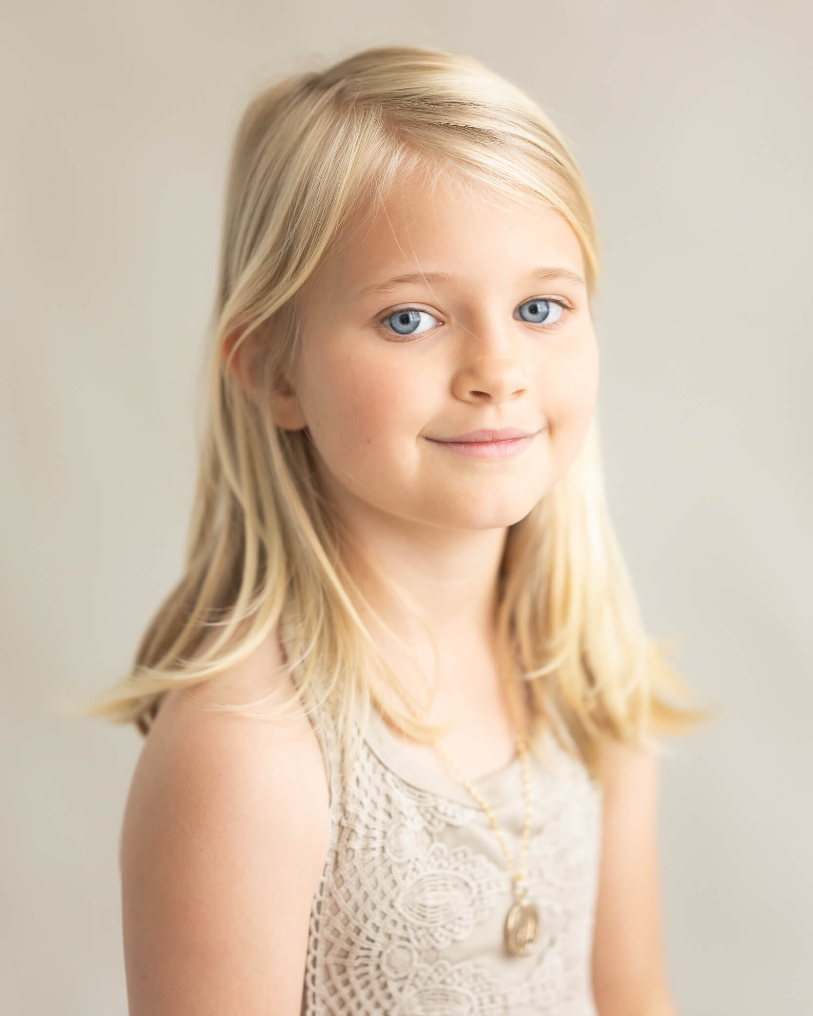 Beautiful studio portrait of young girl with blue eyes in beige dress