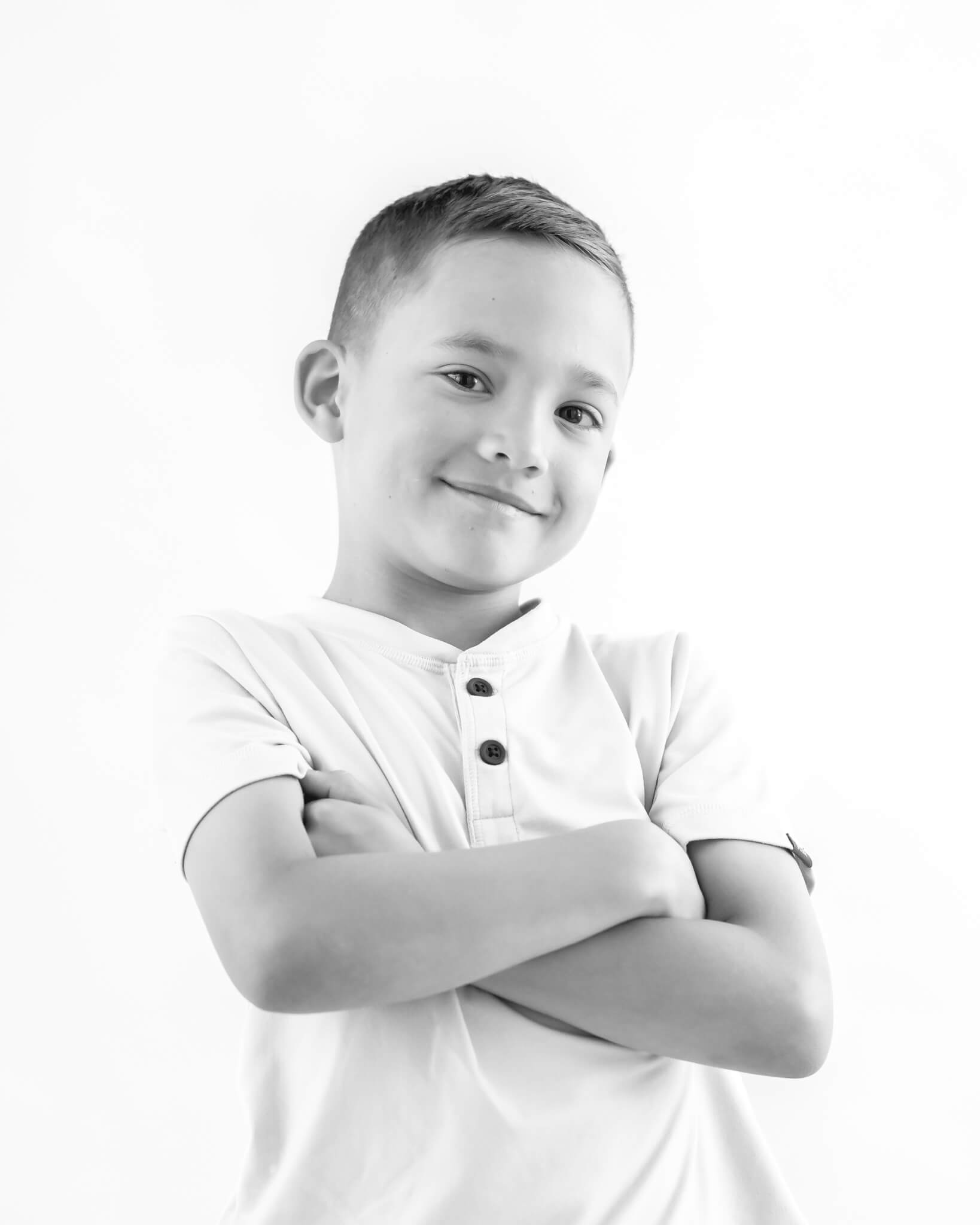 adorable boy arms crossed in black and white studio portrait on white background