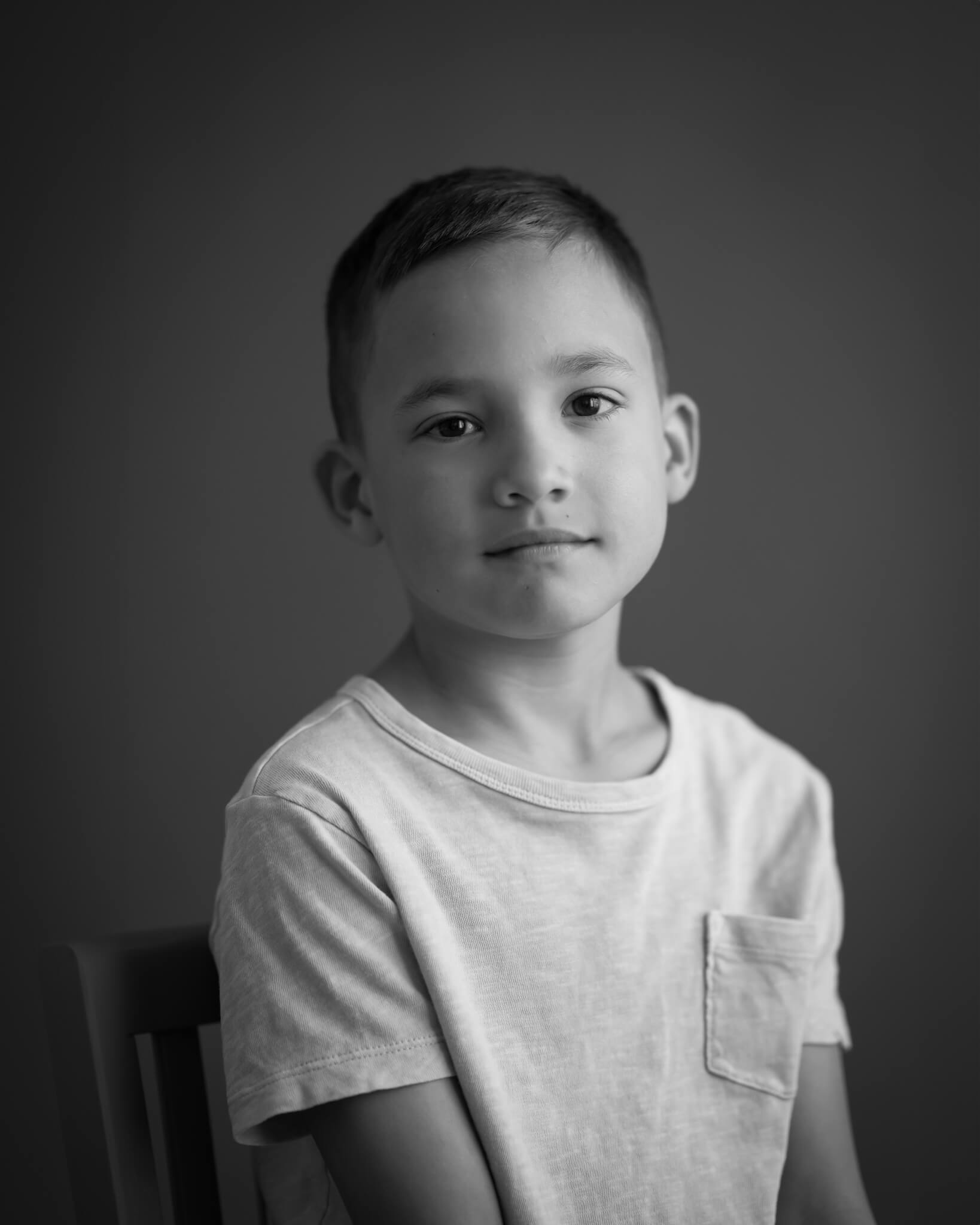 Dramatic B&W Studio portrait in studio of child with serious expression