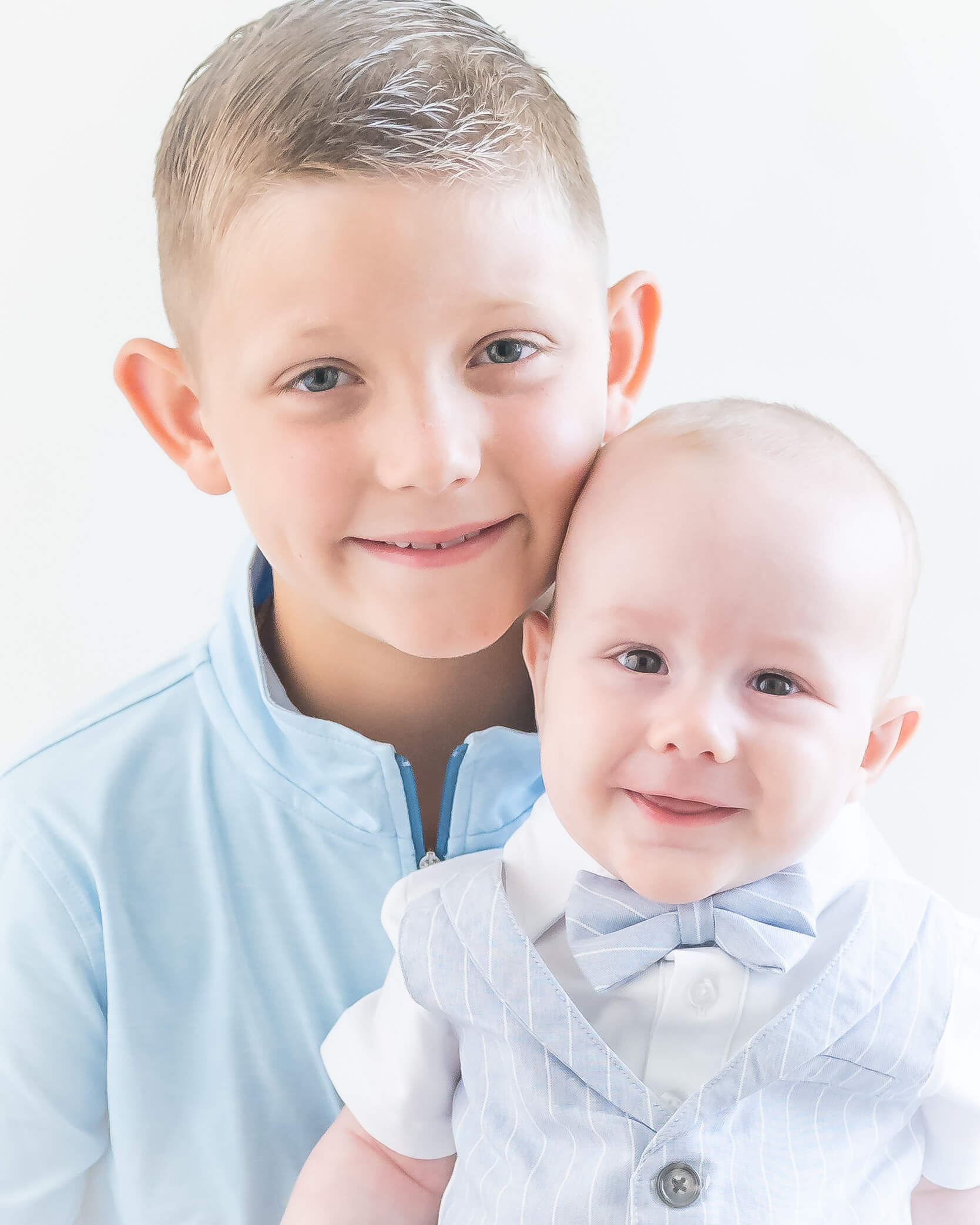 Brothers wearing light blue and white with light background, 6 months and 8 years old