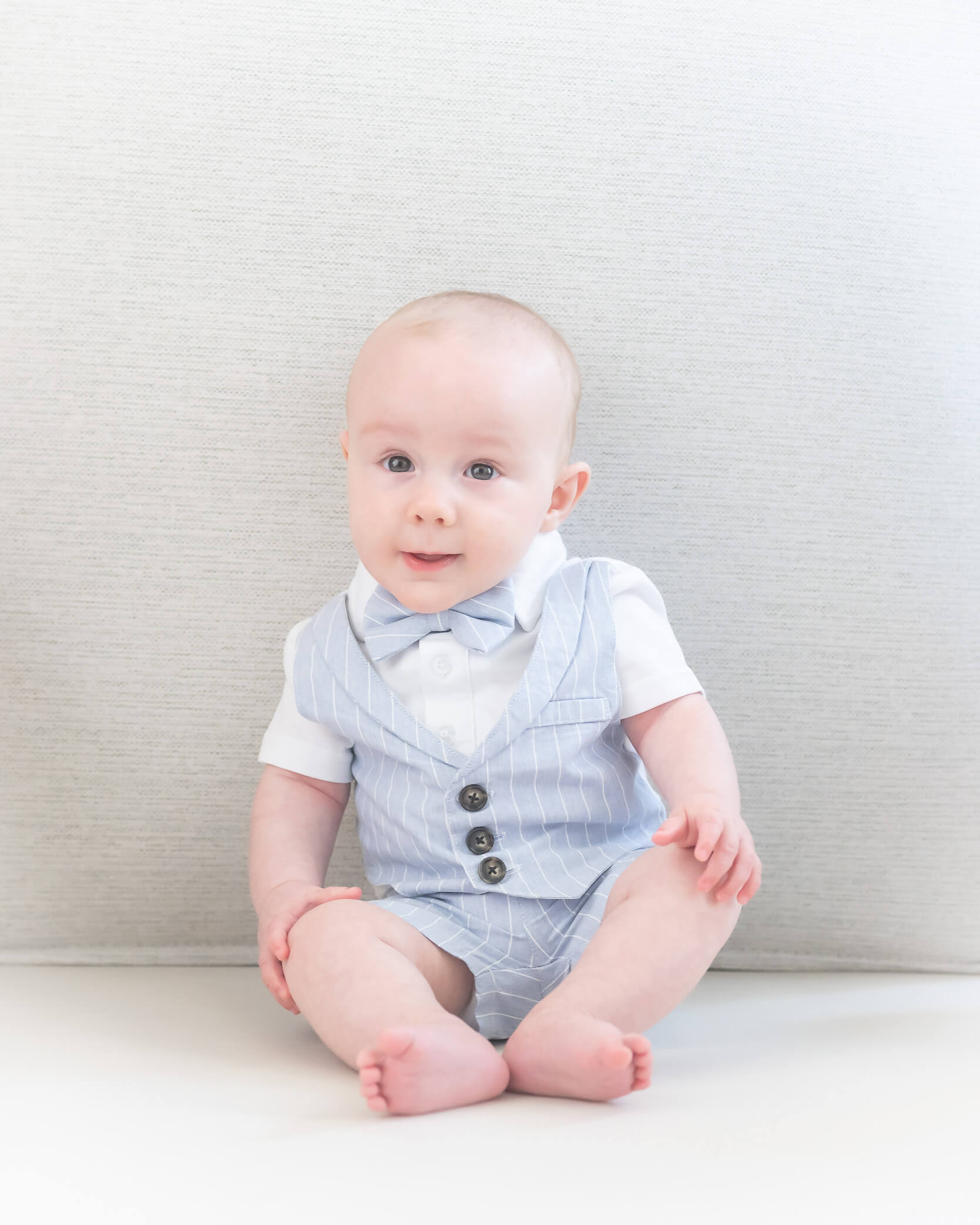 6 month old baby sitting in blue and white little summer suit