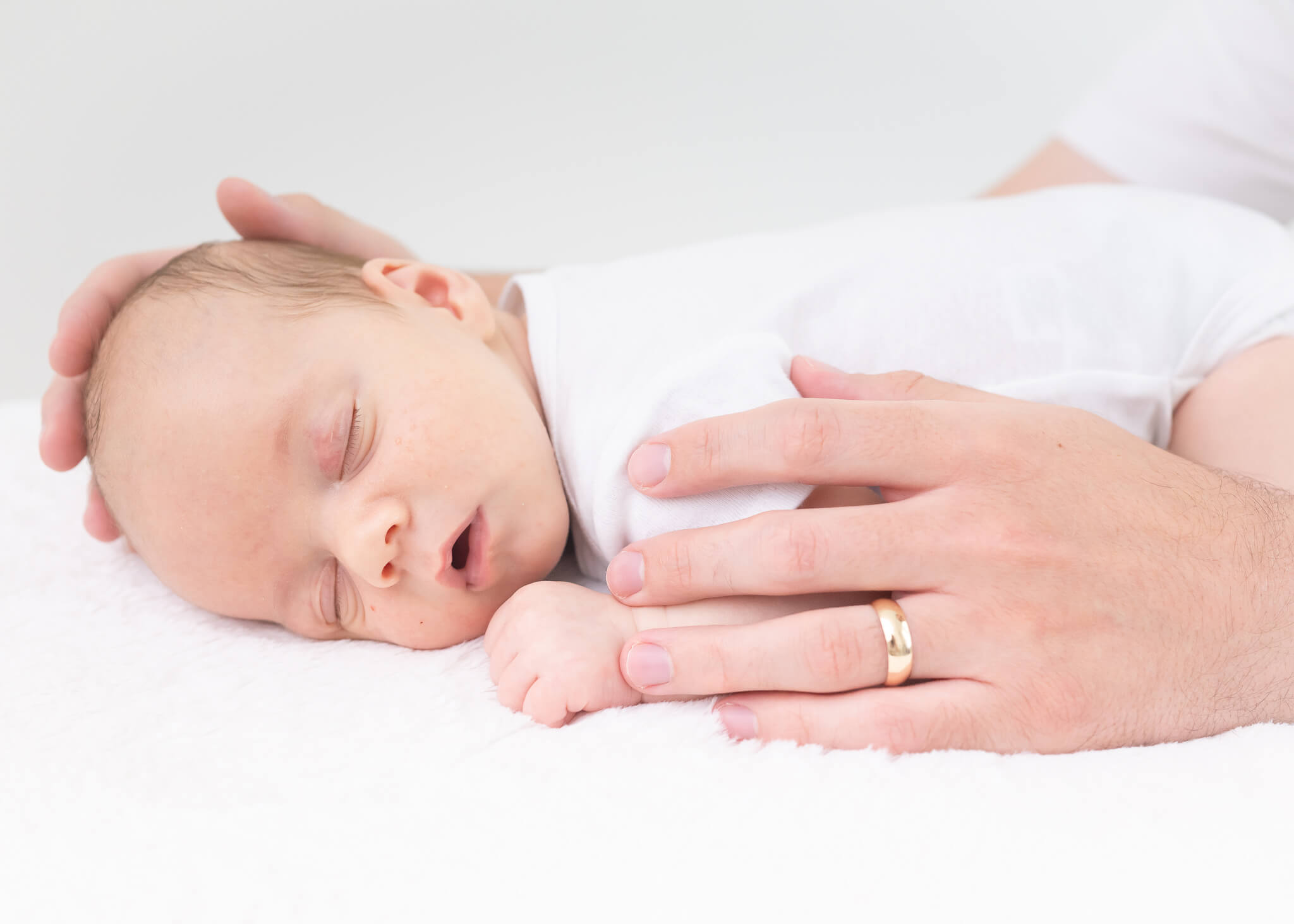 precious baby sleeping with dad's hands on him