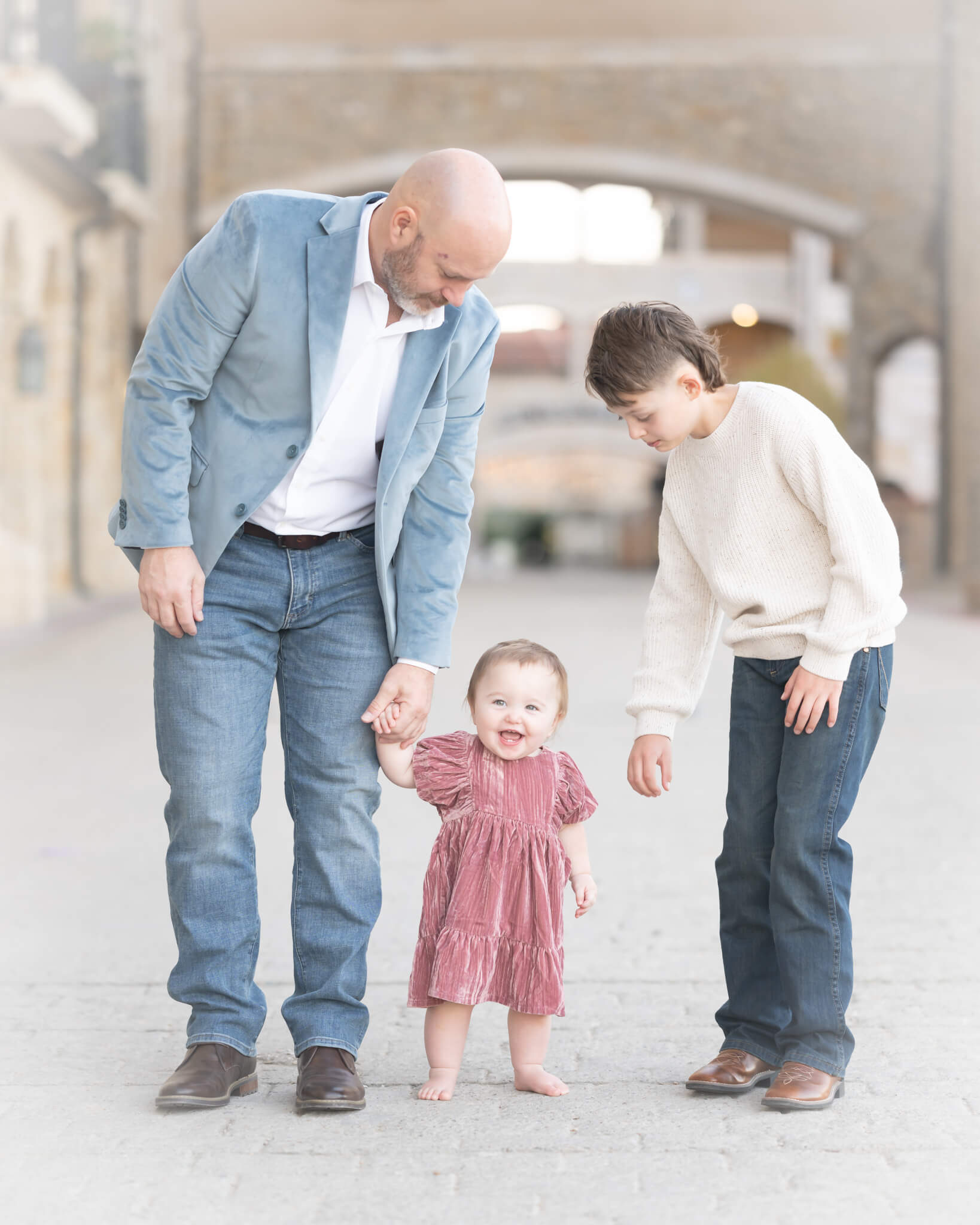 Dad and son with baby girl practicing walking in beautiful family portrait