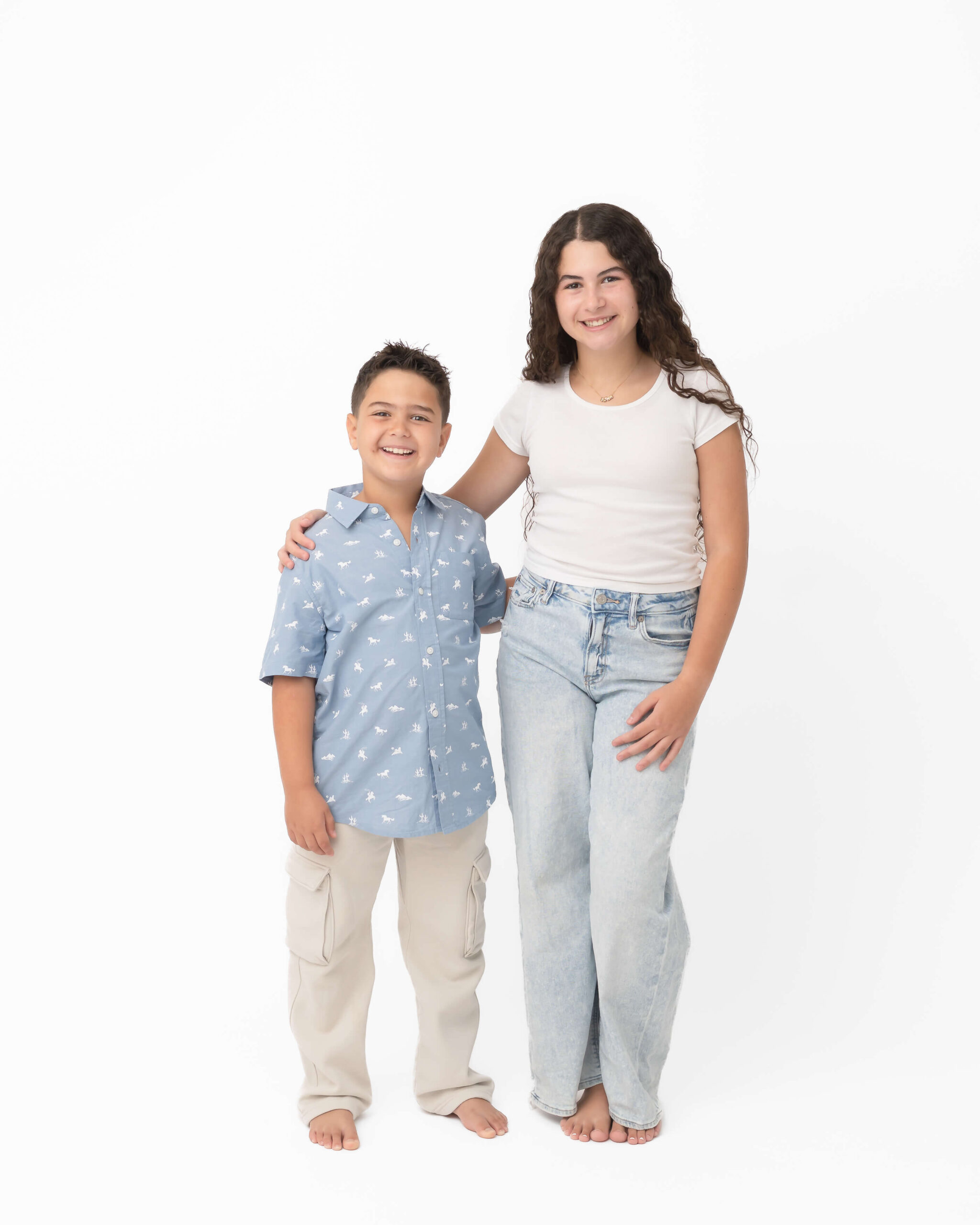 siblings in light neutrals in white studio portrait